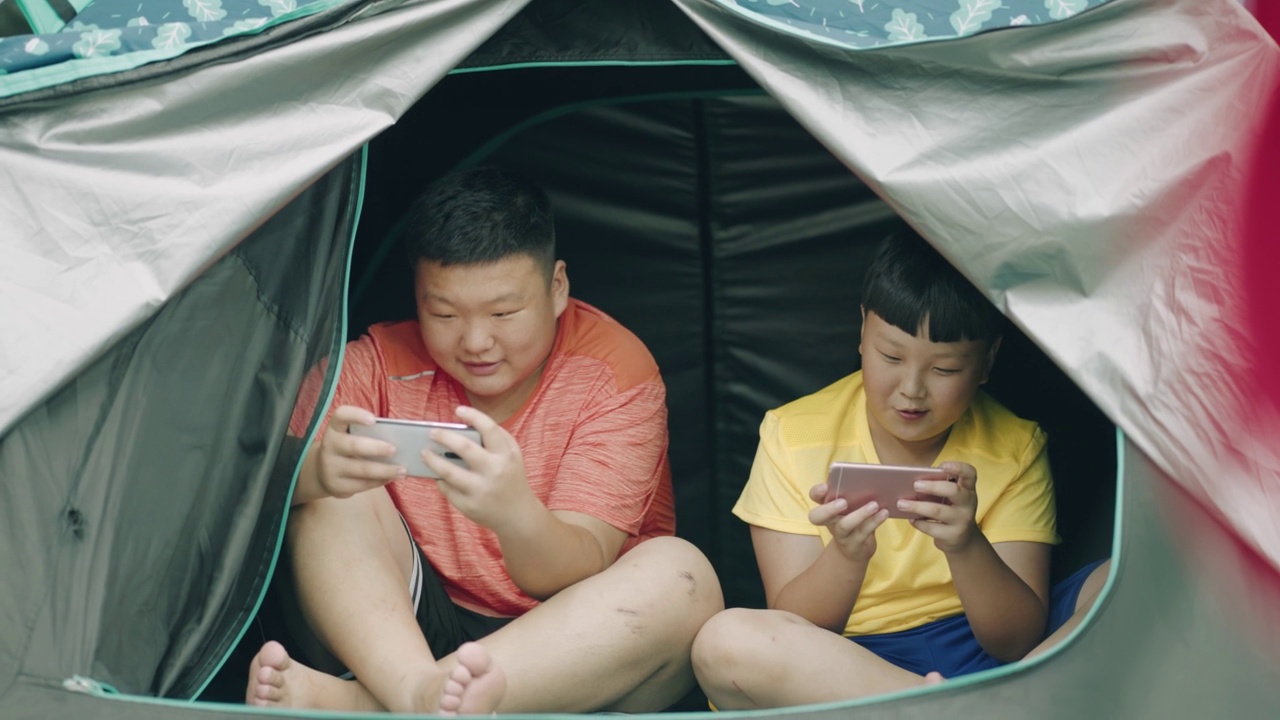 青少年在帐篷里玩智能手机视频素材