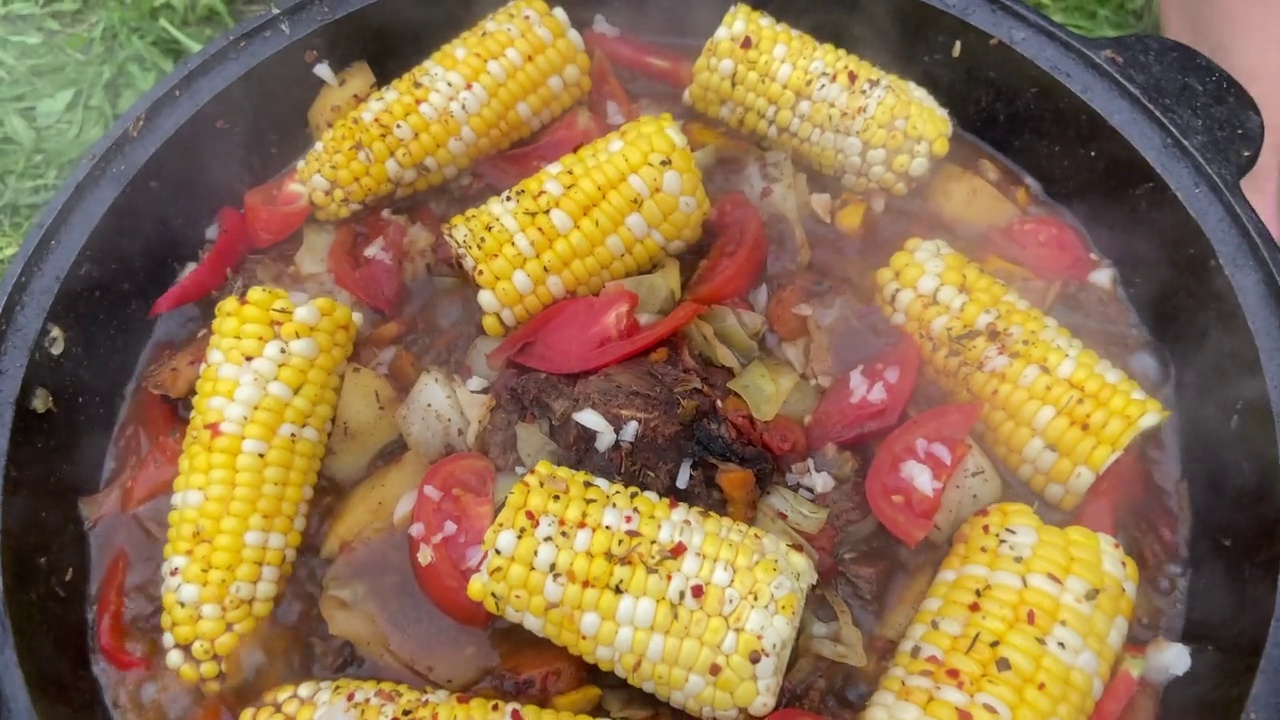 玉米配牛肉和蔬菜。舒尔巴在大锅里。番茄，红辣椒和羊肉汤在热炭上煮。视频下载