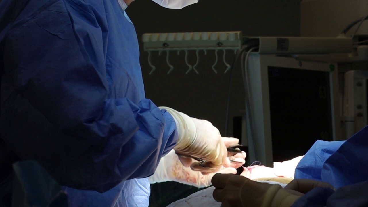 4K真实手术团队完成手术。外科医生和护士戴着无菌手套用线缝合伤口。视频素材