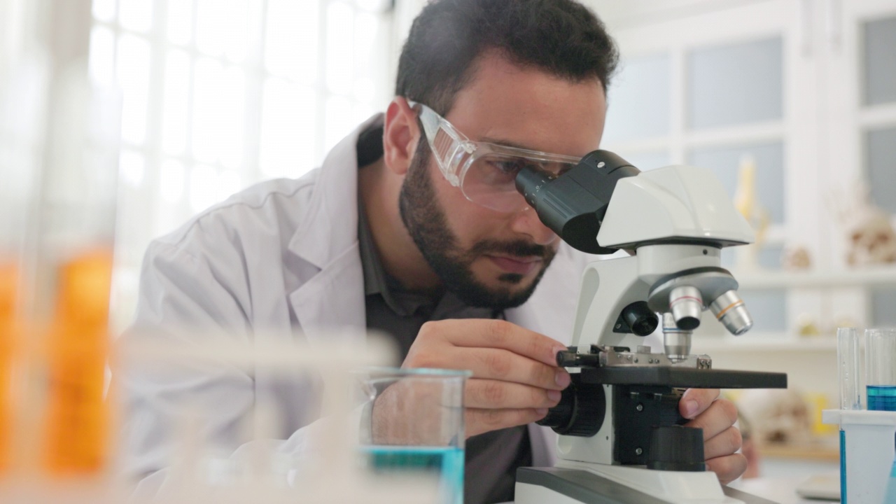 年轻的科学家正在实验室里用显微镜观察。视频下载