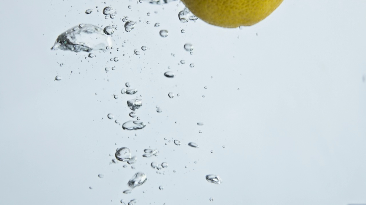浅背景特写中的新鲜柠檬水滴。有机热带水果视频下载