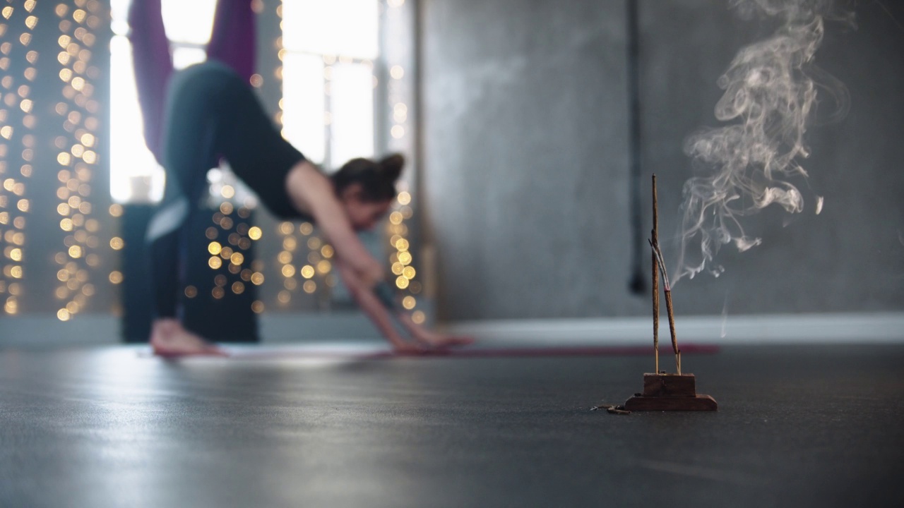 前景的熏香-一个女人在地板上铺开瑜伽垫视频下载