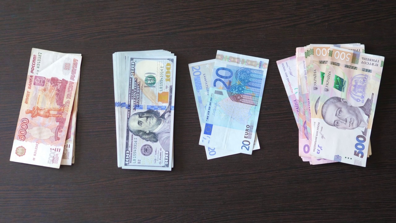 棕色的桌子上放着四摞钞票，美元，欧元，格里夫尼亚，卢布。现金钞票。金融、投资、货币交换、贿赂或腐败的概念。商业上的成功。视频下载