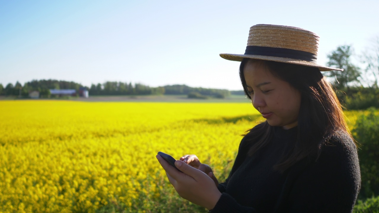特写快乐的亚洲妇女戴着帽子在黄色的田野上拍照视频下载