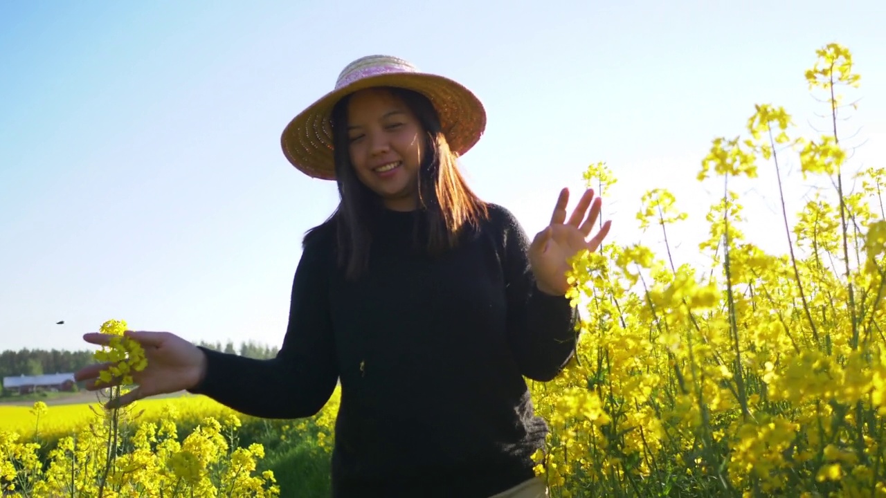 在黄色田野的轨道上，女人走路摸花的正面视图视频下载