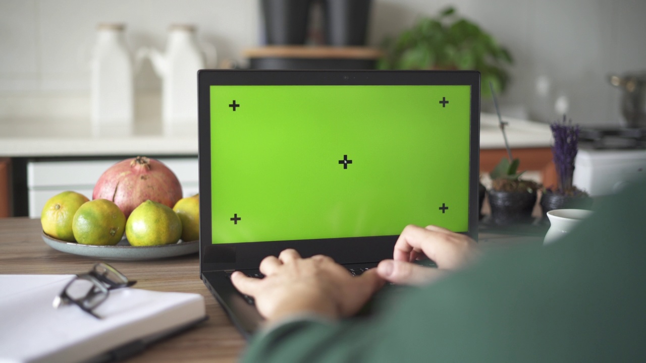 一名男子坐在餐桌前使用绿色屏幕的笔记本电脑视频素材