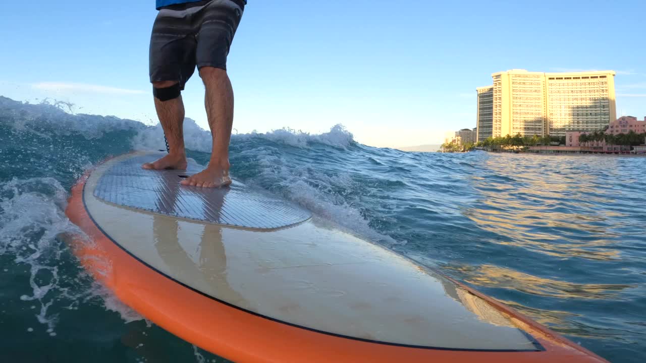 在夏威夷瓦胡岛檀香山的威基基，站起来冲浪，在橙色冲浪板上冲浪。视频下载