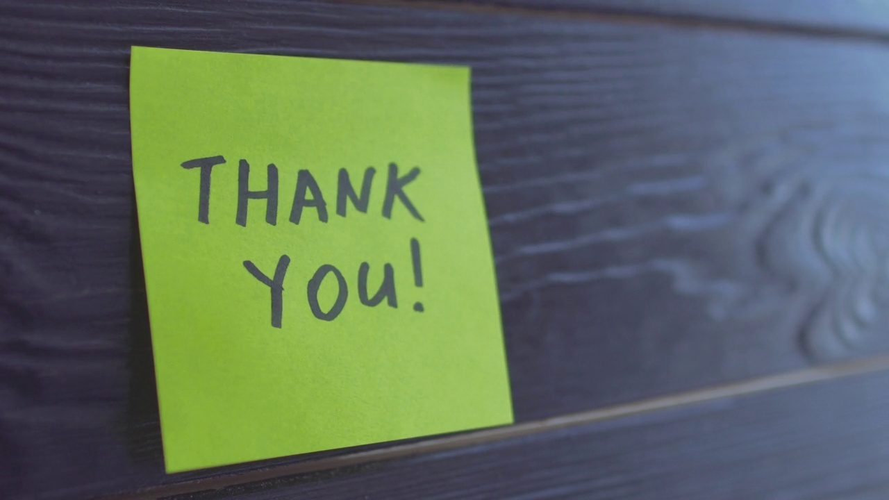 贴纸上写着“谢谢”，孤立在木制背景上视频素材