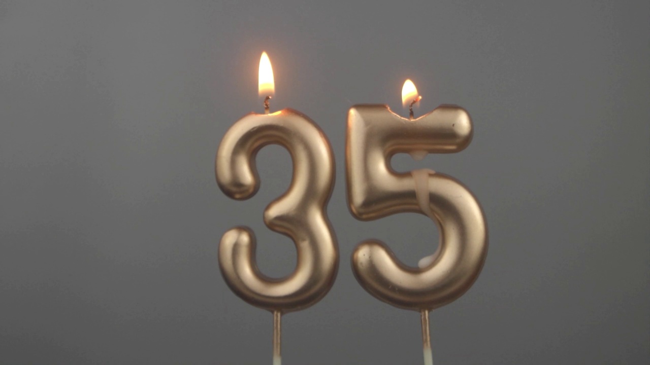 灰色背景下燃烧的金色生日蜡烛，35号视频下载