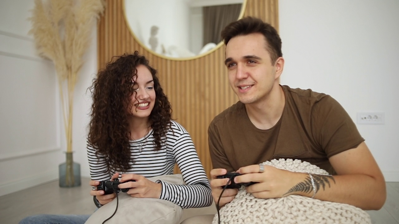年轻夫妇在家里玩游戏机，玩得很开心视频素材