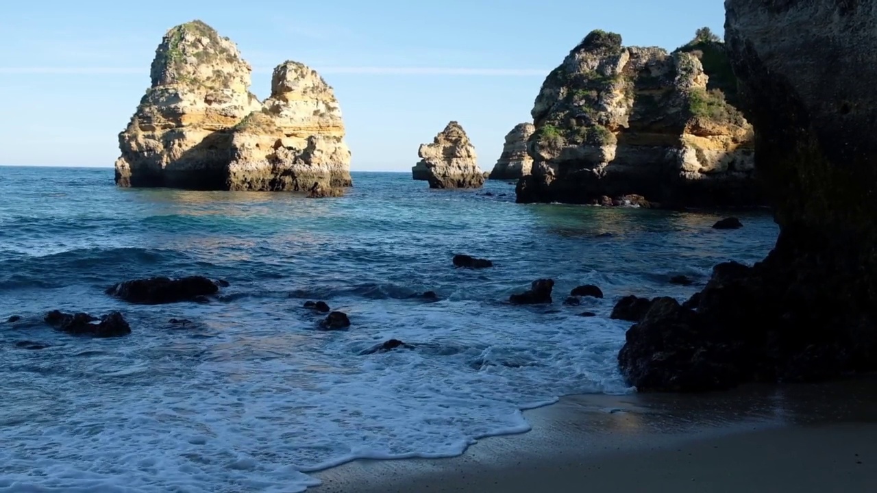 阳光明媚的一天，葡萄牙拉各斯市普拉亚多娜安娜海滩上的岩石视频素材