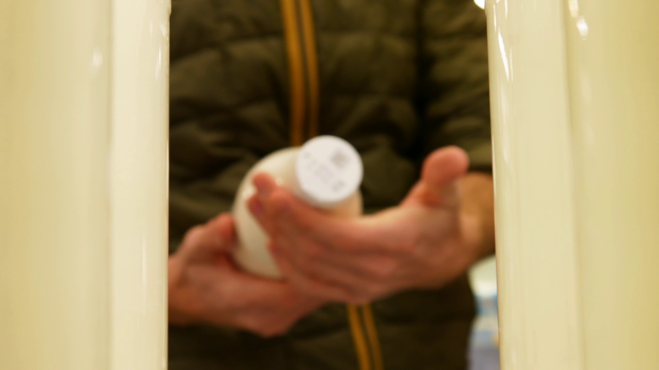 商店冰箱架子上的牛奶瓶的特写，一个男性买家拿了一个视频素材