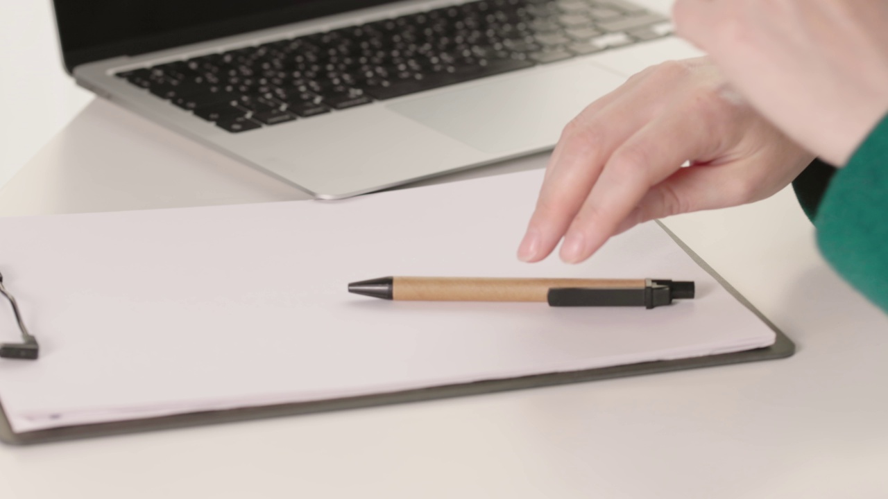 特写女性手拿笔开始写白纸手写笔记本电脑视频素材