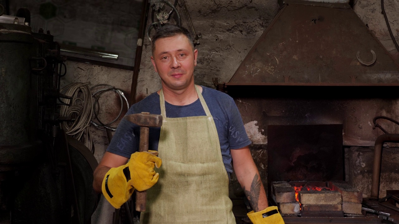 一个老铁匠铺里拿着锤子和大钳子的铁匠肖像。视频下载