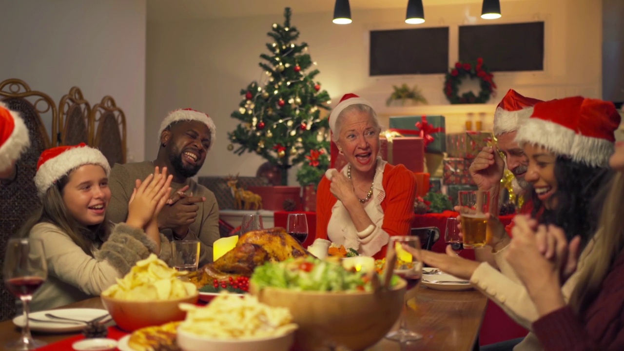 一个多民族的群体。白人和非裔美国黑人家庭的画像，妇女在圣诞夜的聚会上有一个庆祝晚餐在圣诞假期在家。人们的生活方式。感恩节视频下载