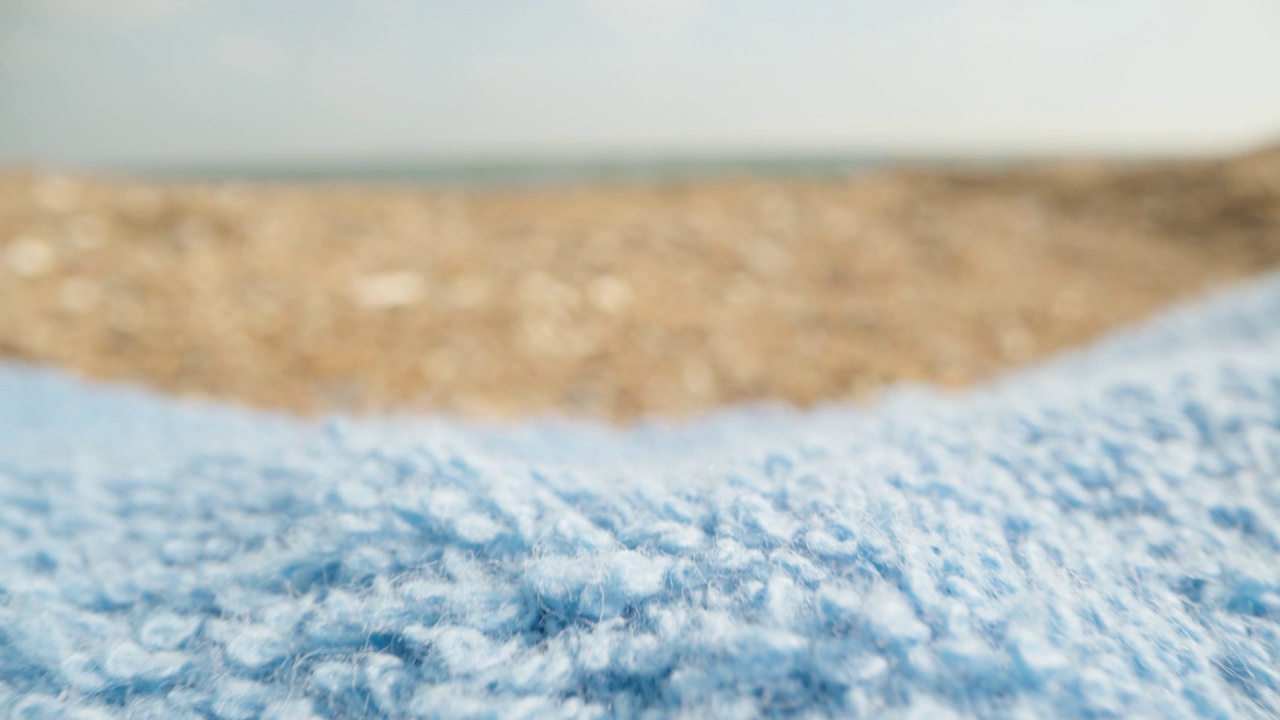 海边的蓝色毛巾，质感，与大海的背景相映成趣。洋娃娃滑块极限特写。视频素材