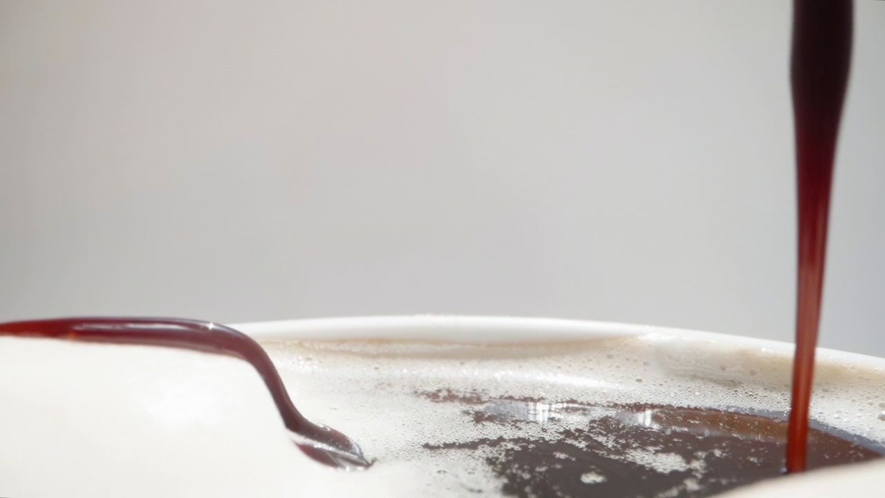 我把巧克力倒在棉花糖上。棉花糖漂浮在白色马克杯里的咖啡中，慢动作。洋娃娃滑块极限特写。视频素材