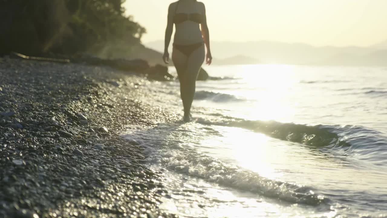 美丽的场景，一个低部分的妇女走在海滩上的日落视频素材