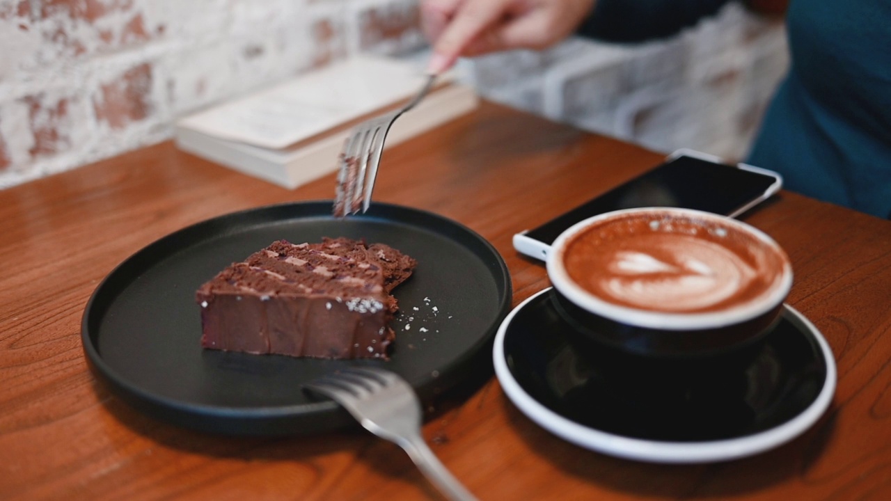 女人拿着一块巧克力蛋糕和一杯咖啡视频下载