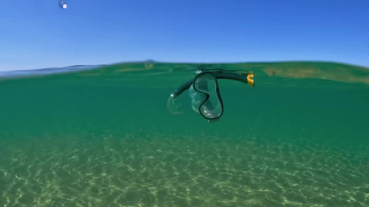 不寻常的半水下视图丢失潜水面罩与浮管漂浮在海水表面与背景钓鱼木平台。意大利的Abruzzo，慢镜头视频下载