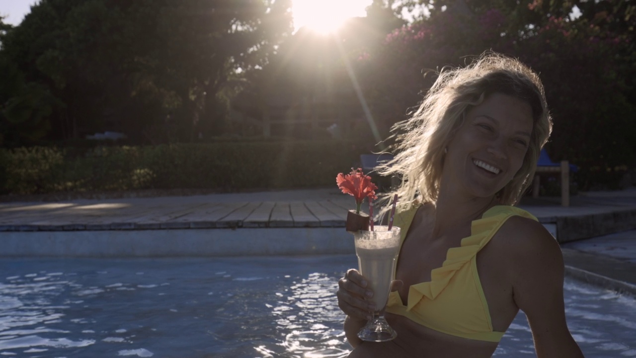 快乐的女人在夏日的泳池里喝着冰沙。视频素材