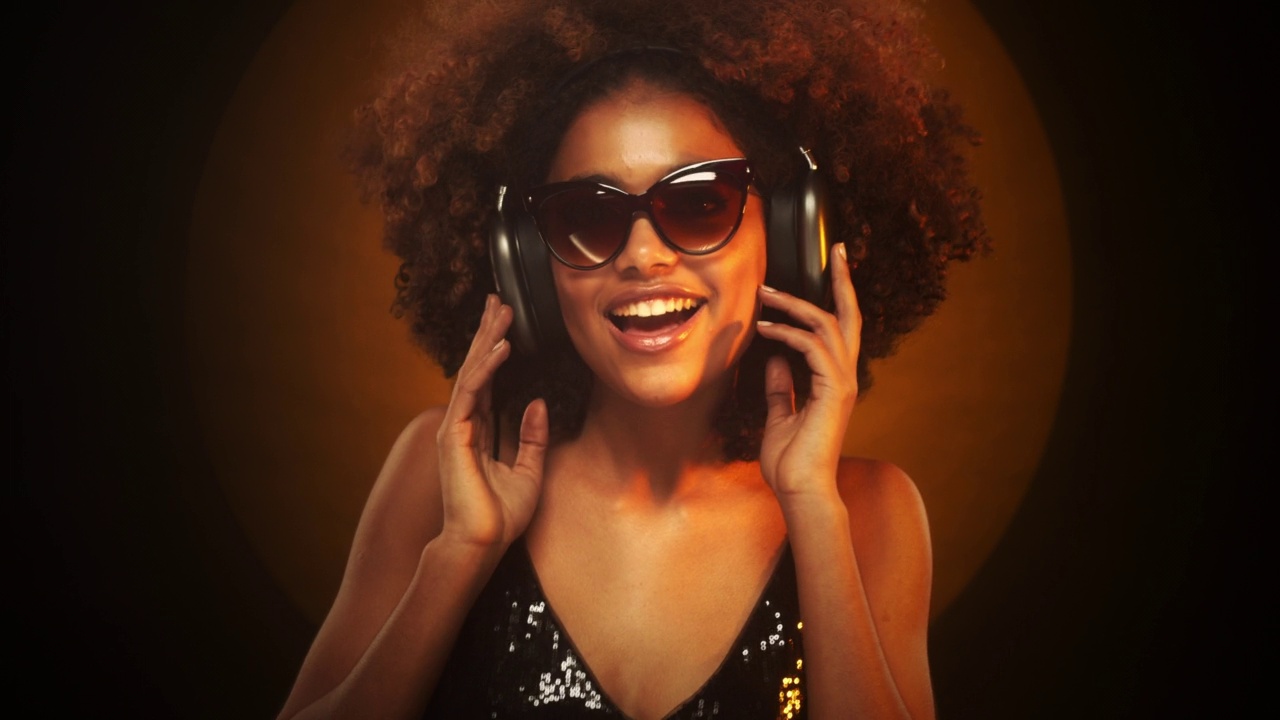 非洲女孩戴着耳机听音乐，孤立在棕色的录音棚背景上视频素材