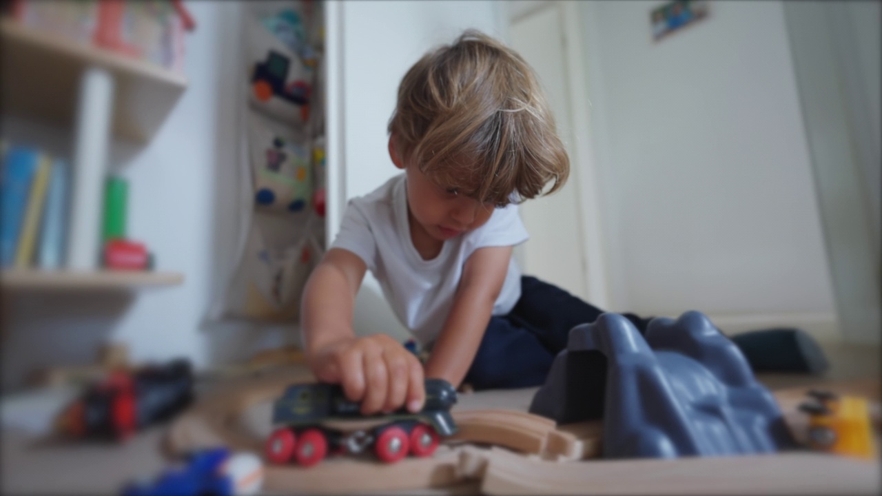 孩子在房间里玩耍。一个小孩自己玩玩具。小男孩在卧室，家里的地板上有铁轨视频素材