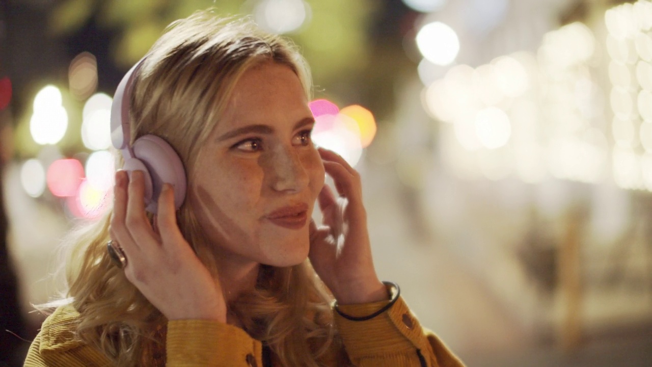 女子戴着耳机在晚上听音乐视频素材