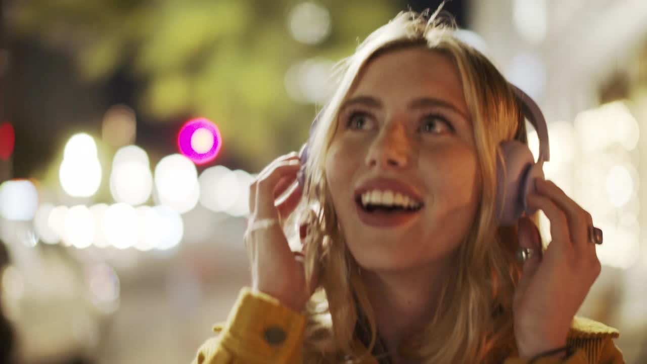 夜间城市里戴着耳机的年轻女子视频素材