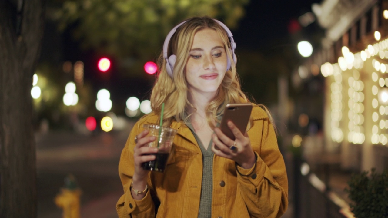 夜晚在城市里用手机散步的年轻女子视频素材