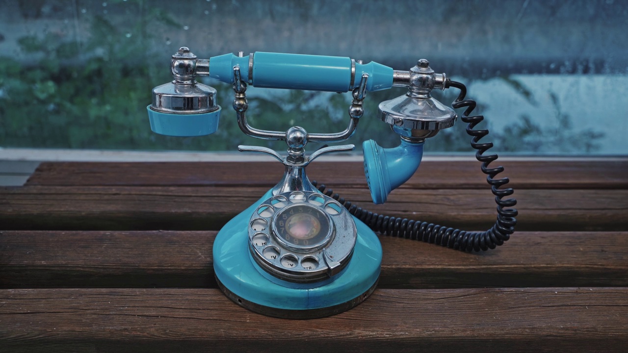 一个女人的手拿起一个老式的蓝色旋转式电话听筒打电话。老式手机。视频素材