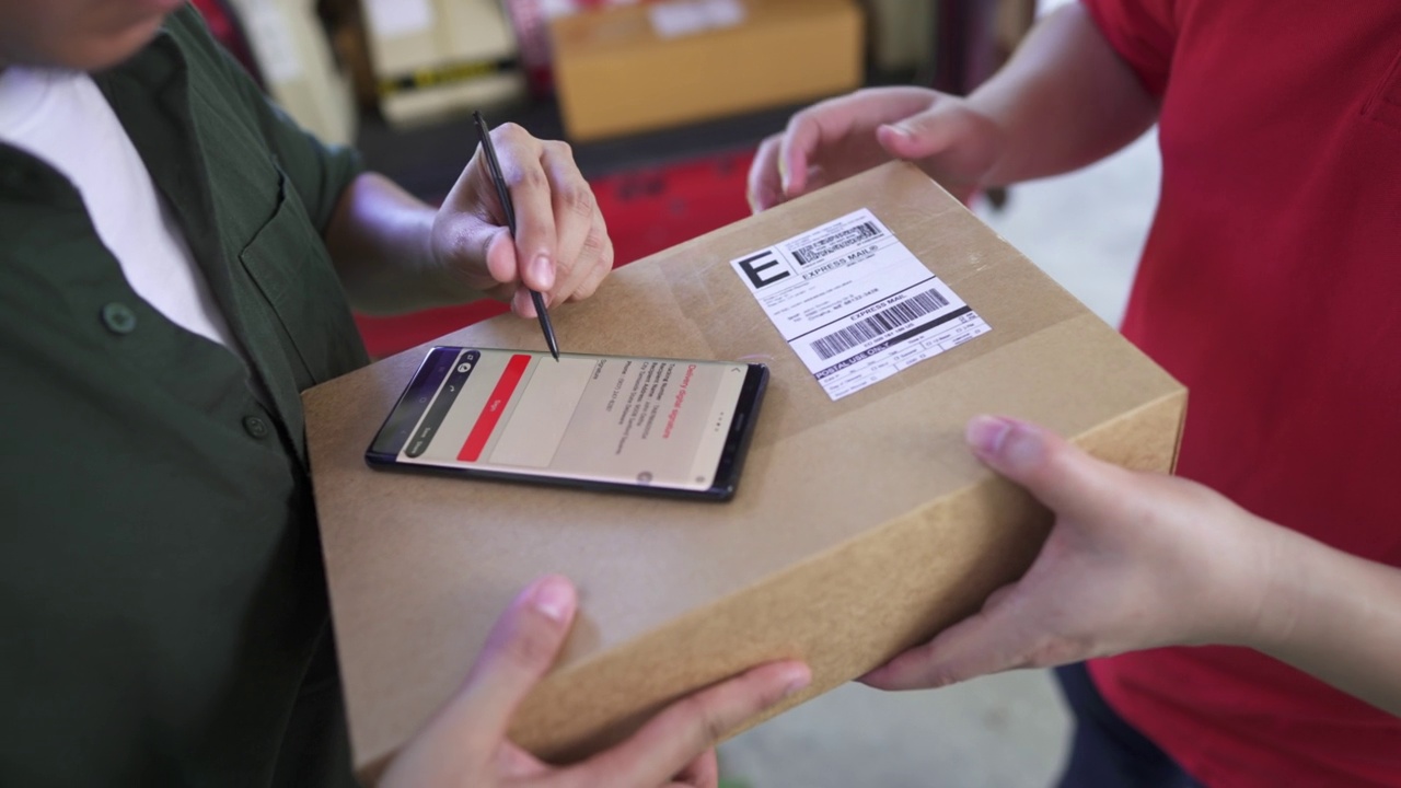 快递员收到快递公司员工的包裹，并在员工的智能手机上进行电子签名。视频下载