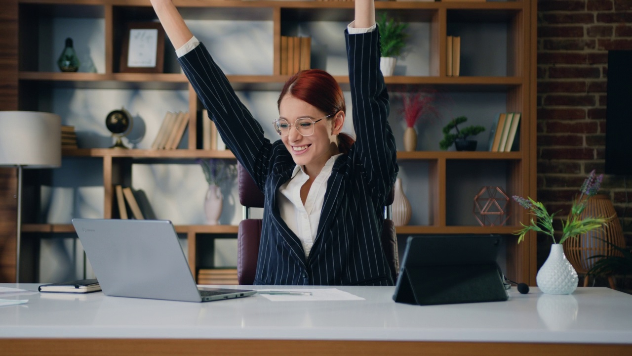 快乐的商业女性阅读好消息微笑享受商业成功在办公室。商务女士检查电子邮件庆祝成功，胜利，惊喜和举手。视频素材
