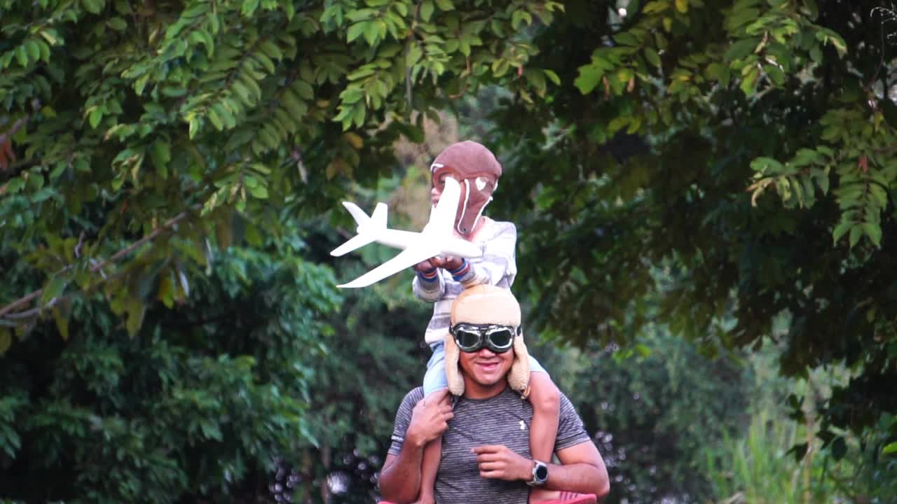 戴着飞行员眼镜的男孩和爸爸在公园里玩飞行游戏视频素材