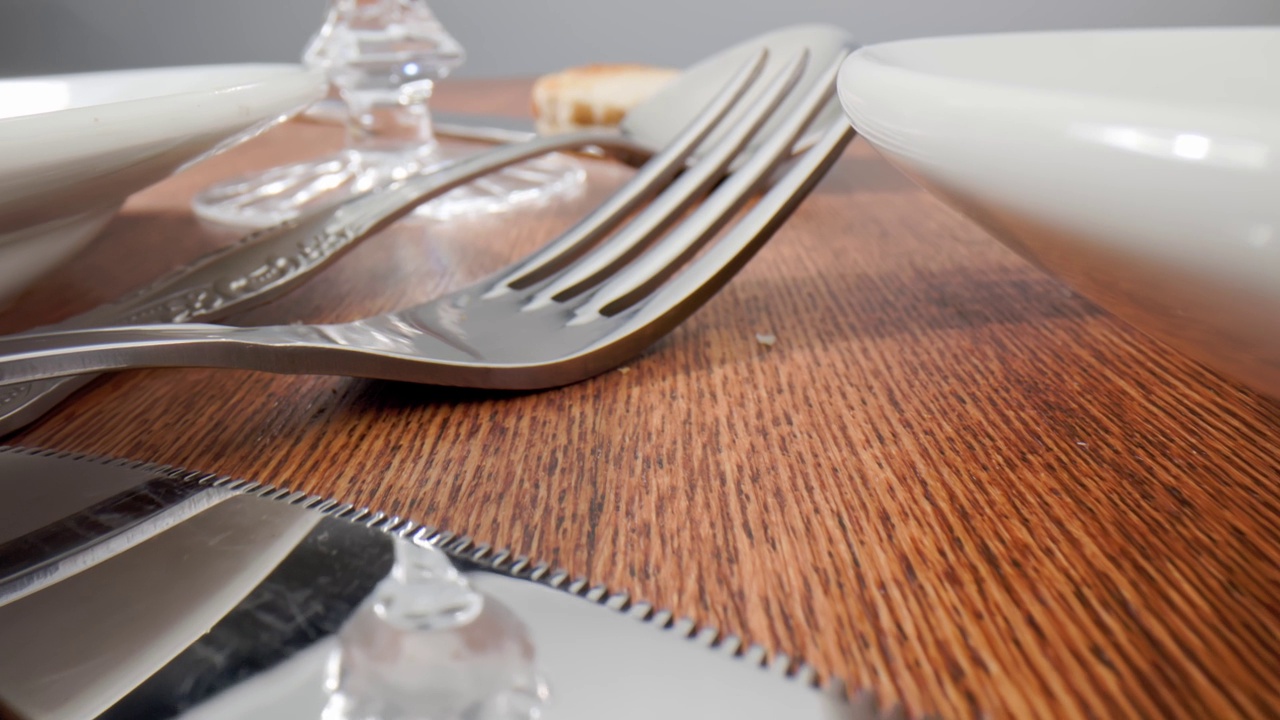 聚会后放着剩菜和餐具的木桌。水晶玻璃，盘子，刀叉都很近。视频下载