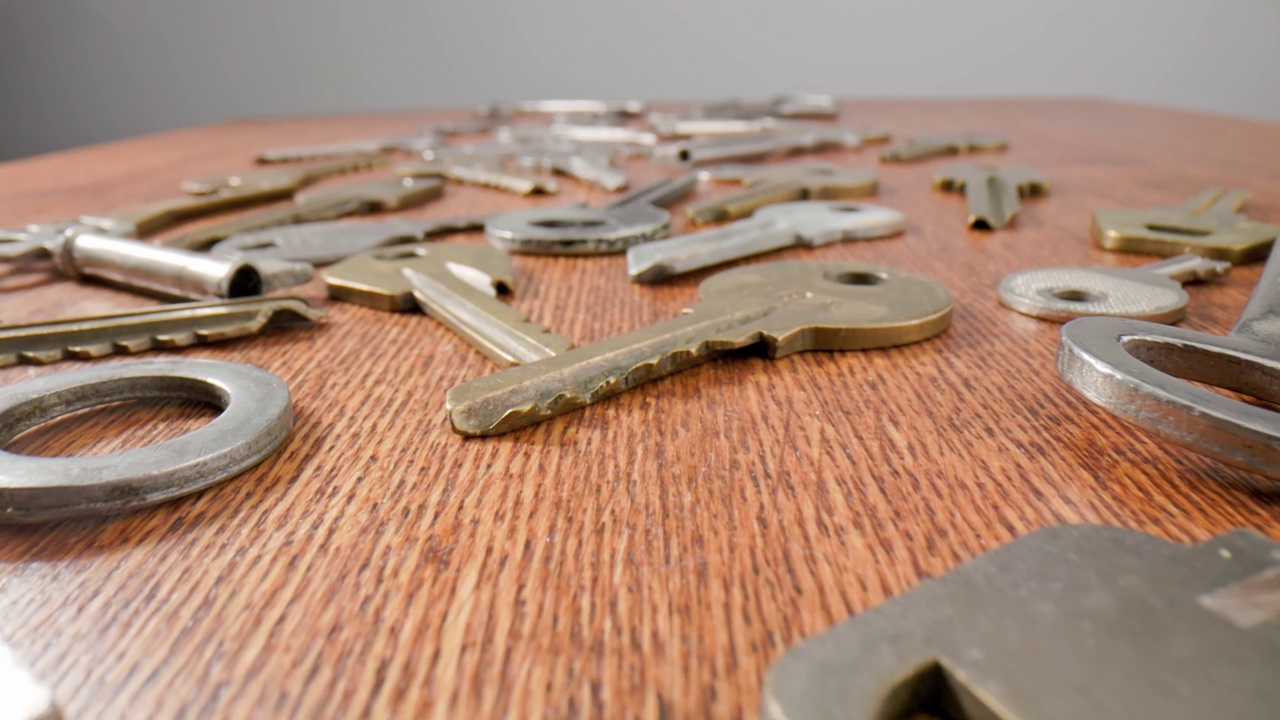 镜头移动的键躺在一个旧的木制背景。男人的手指拿着钥匙。视频下载