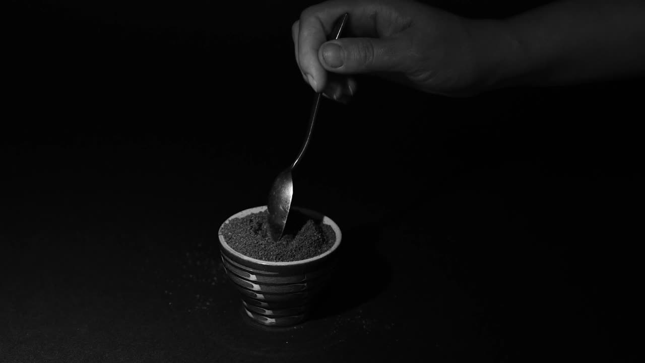 磨碎的咖啡从勺子慢慢地掉到杯子里，杯子里装满了磨碎的咖啡。视频下载
