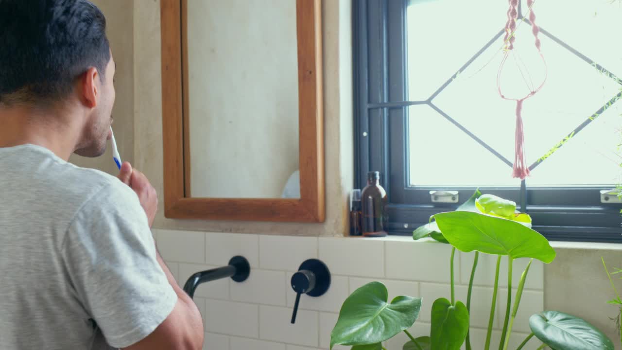 男士将牙刷放在浴室镜子上，以保持牙齿健康或口腔卫生或护理。年轻的亚洲男性早上在家里用牙刷清洁牙齿，美容，健康和保健视频素材