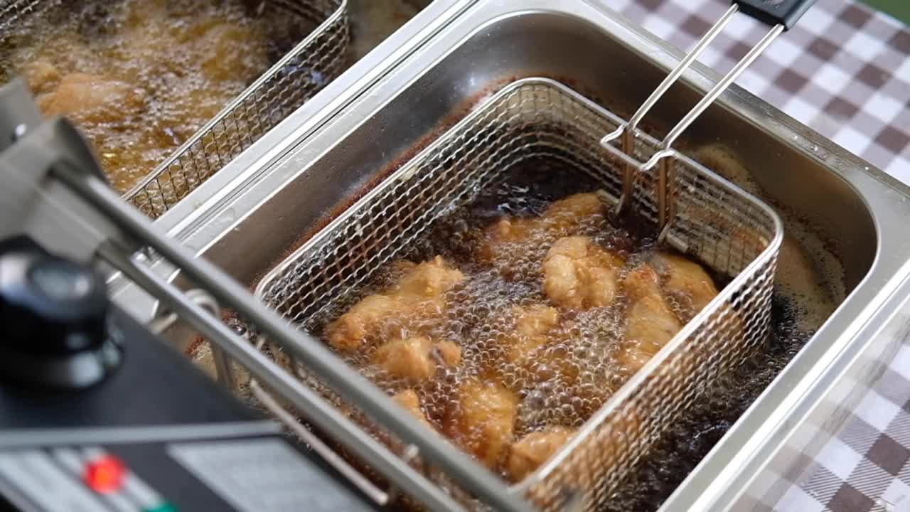在油炸锅里炸鸡肉时，油的气泡是沸腾的。视频下载