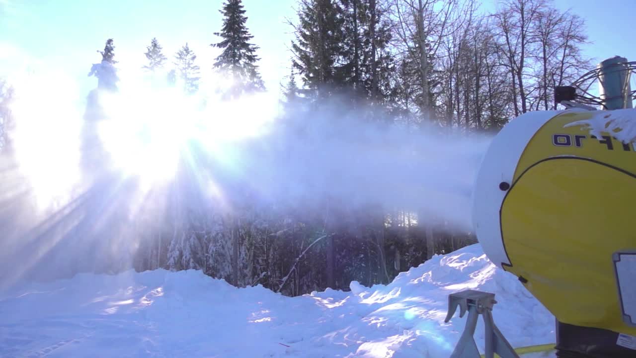 雪炮在迎着日出的斜坡上制造人造雪，慢镜头视频素材