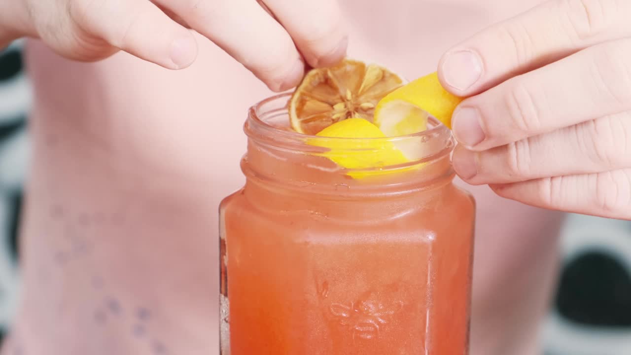 特写调酒师用柠檬皮和干橙装饰鸡尾酒。鸡尾酒的准备视频素材
