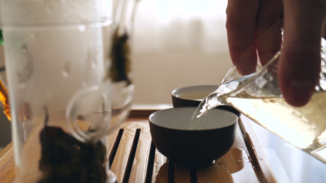 一名茶师将神奇的中国茶倒入碗中，这是一场地道的中国仪式。正宗的茶具。慢动作视频下载