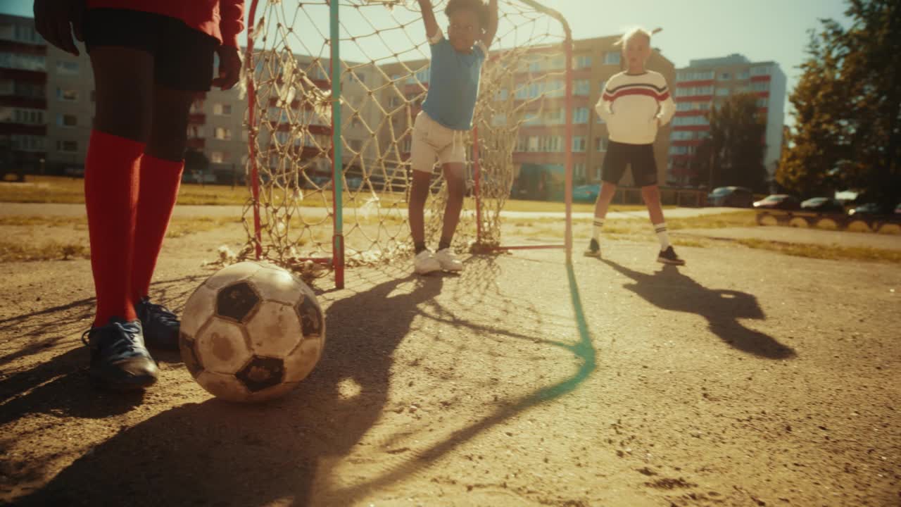 年轻的黑人男孩和朋友踢足球。多民族的孩子们在附近玩足球。球员与队友一起庆祝进球。快节奏跟踪镜头。视频下载