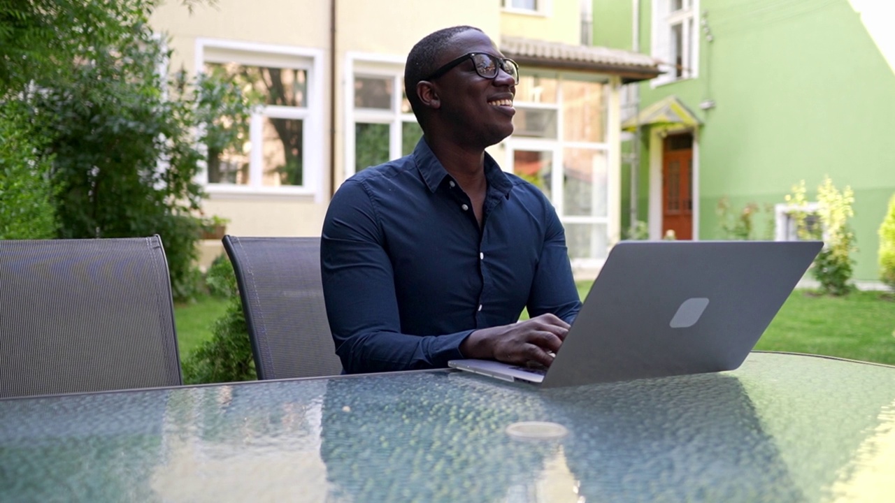微笑的企业家在花园里用笔记本电脑打字视频素材