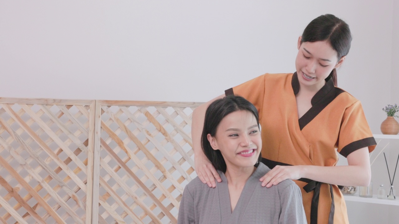 美丽年轻的亚洲女子放松在白色的床上与年轻的按摩水疗治疗专业。泰式水疗沙龙颈肩按摩，生活美女人概念。视频下载