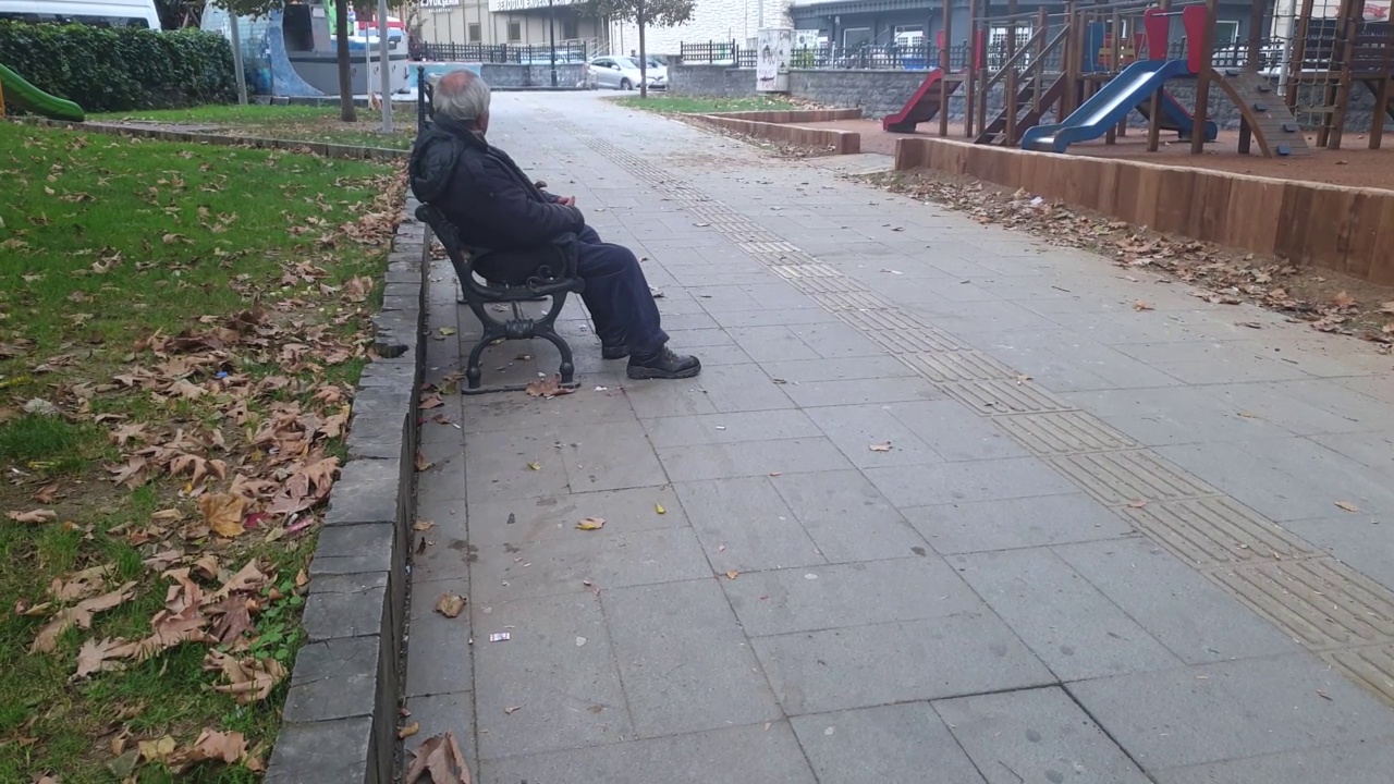 愁眉苦脸的老人坐在城市公园里视频下载