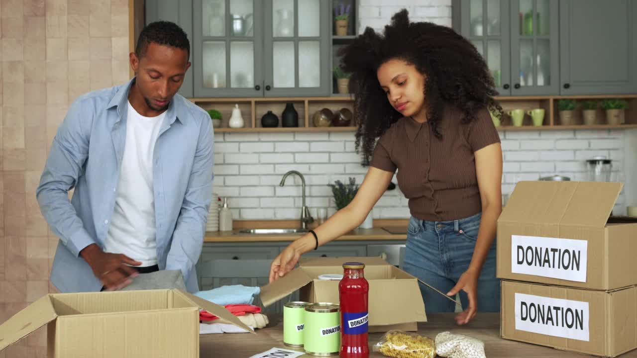 一对年轻夫妇把食品杂货装进慈善箱视频素材