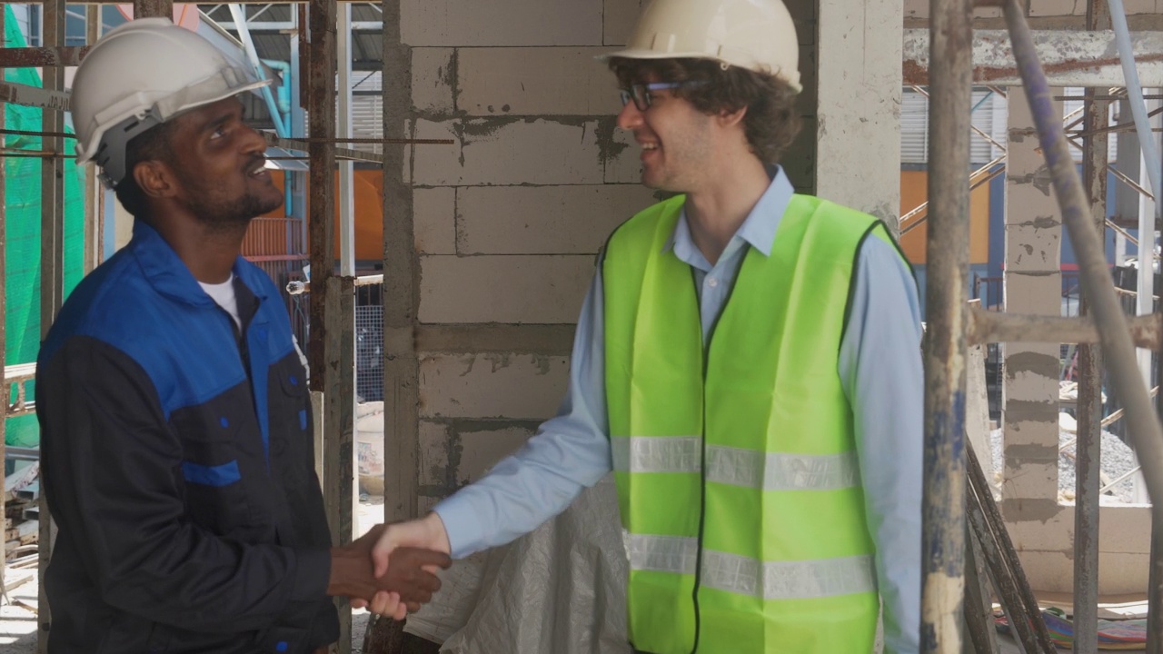 年轻的工头和工人握手为团队合作成就，工程师和施工现场，建筑师握手为成功达成协议，共同交易。视频素材