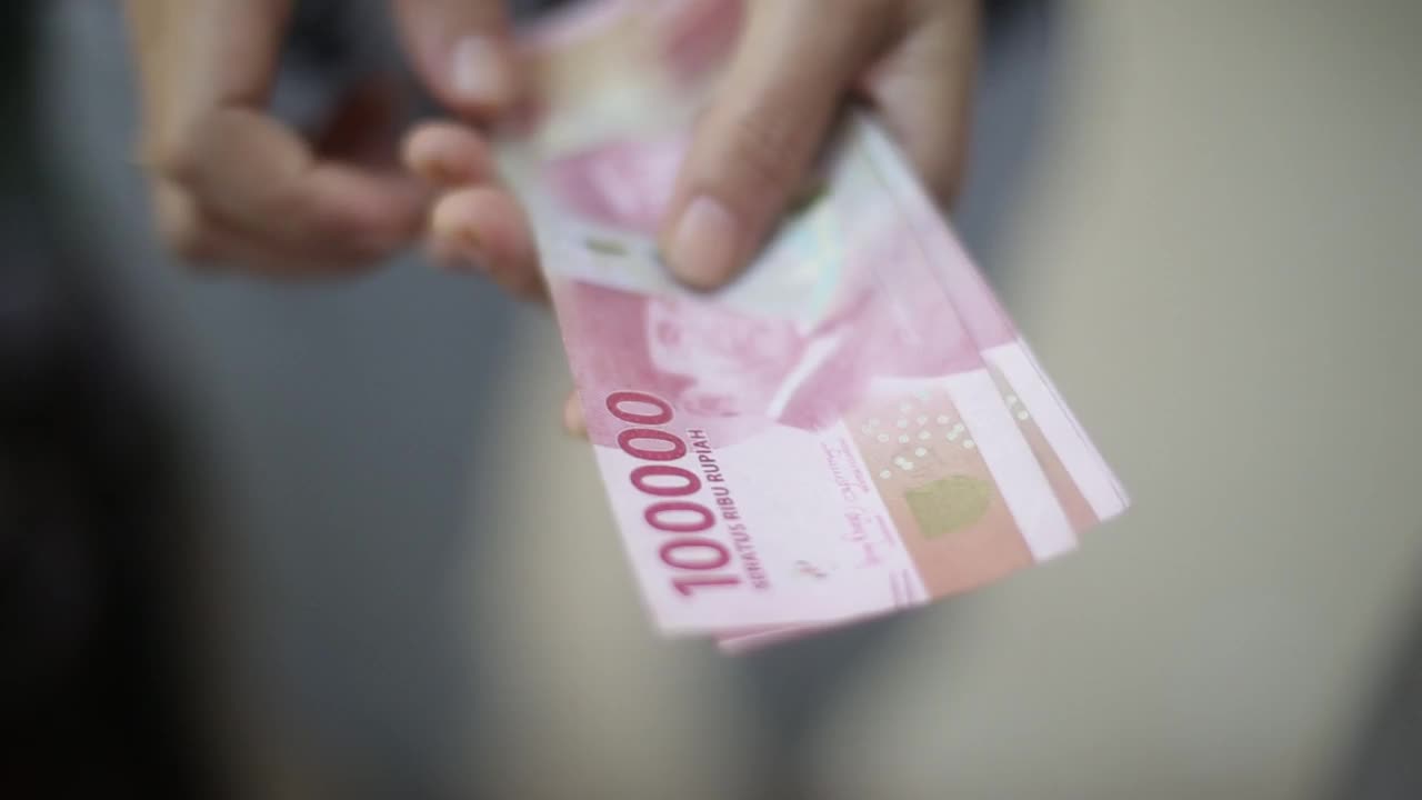 近距离的妇女手数钱光印尼盾和一张纸条将作出，金钱理财理念视频下载