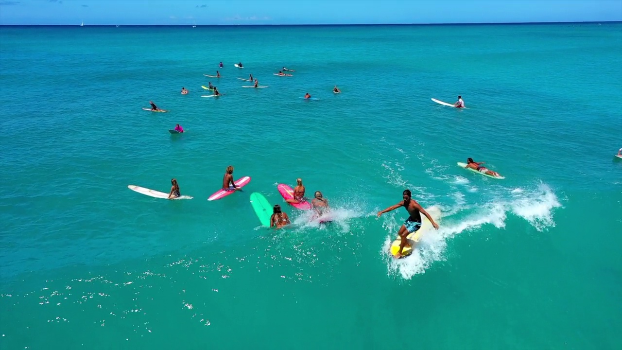 空中倾斜拍摄的男人和女人在阳光灿烂的日子里在蓝色的大海冲浪-怀基基，夏威夷视频下载